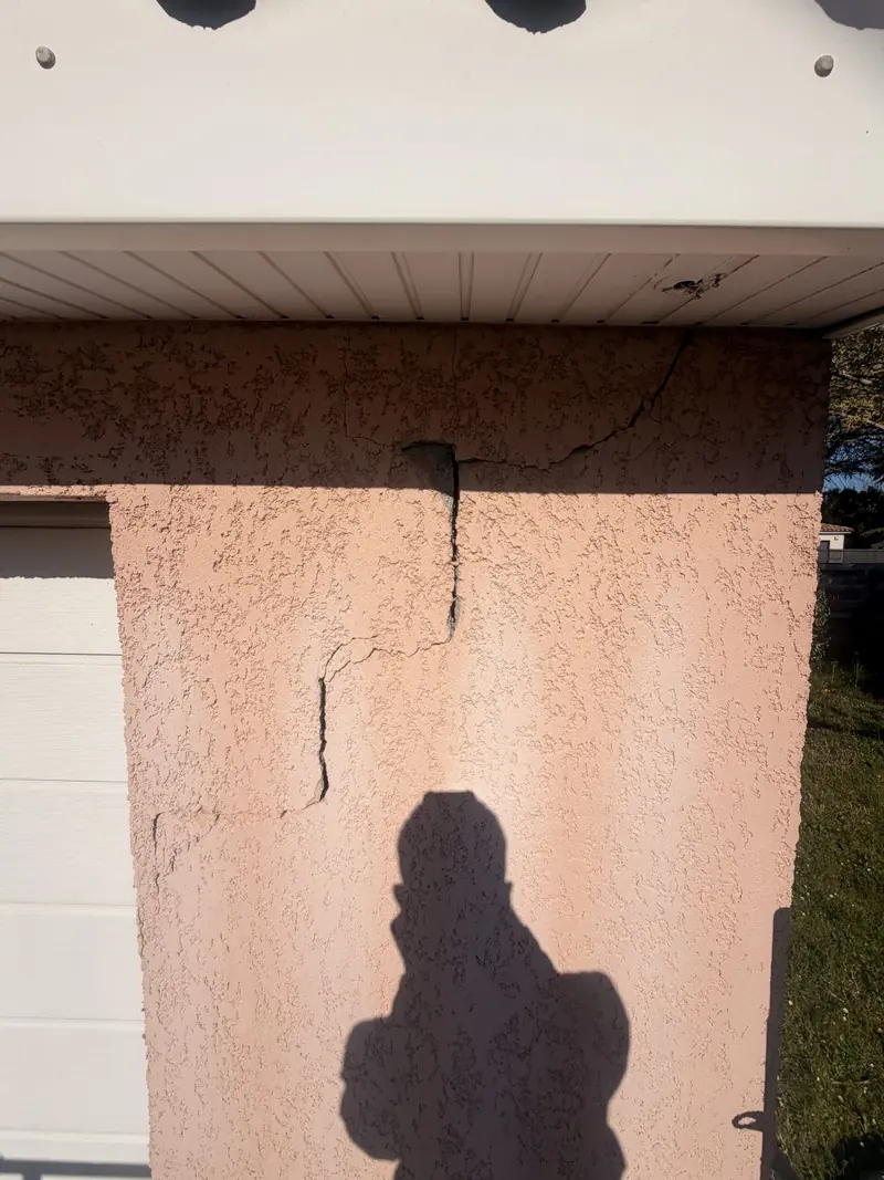Fissure fine sur l'enduit d'une façade, en gros plan avant réparation